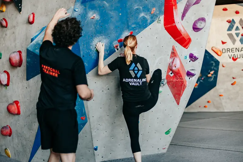 Rick watching a climber's footwork as she steps up on the bouldering wall